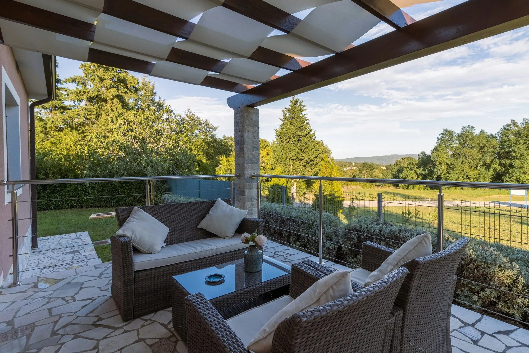 Covered backyard patio with wicker furniture overlooking trees
