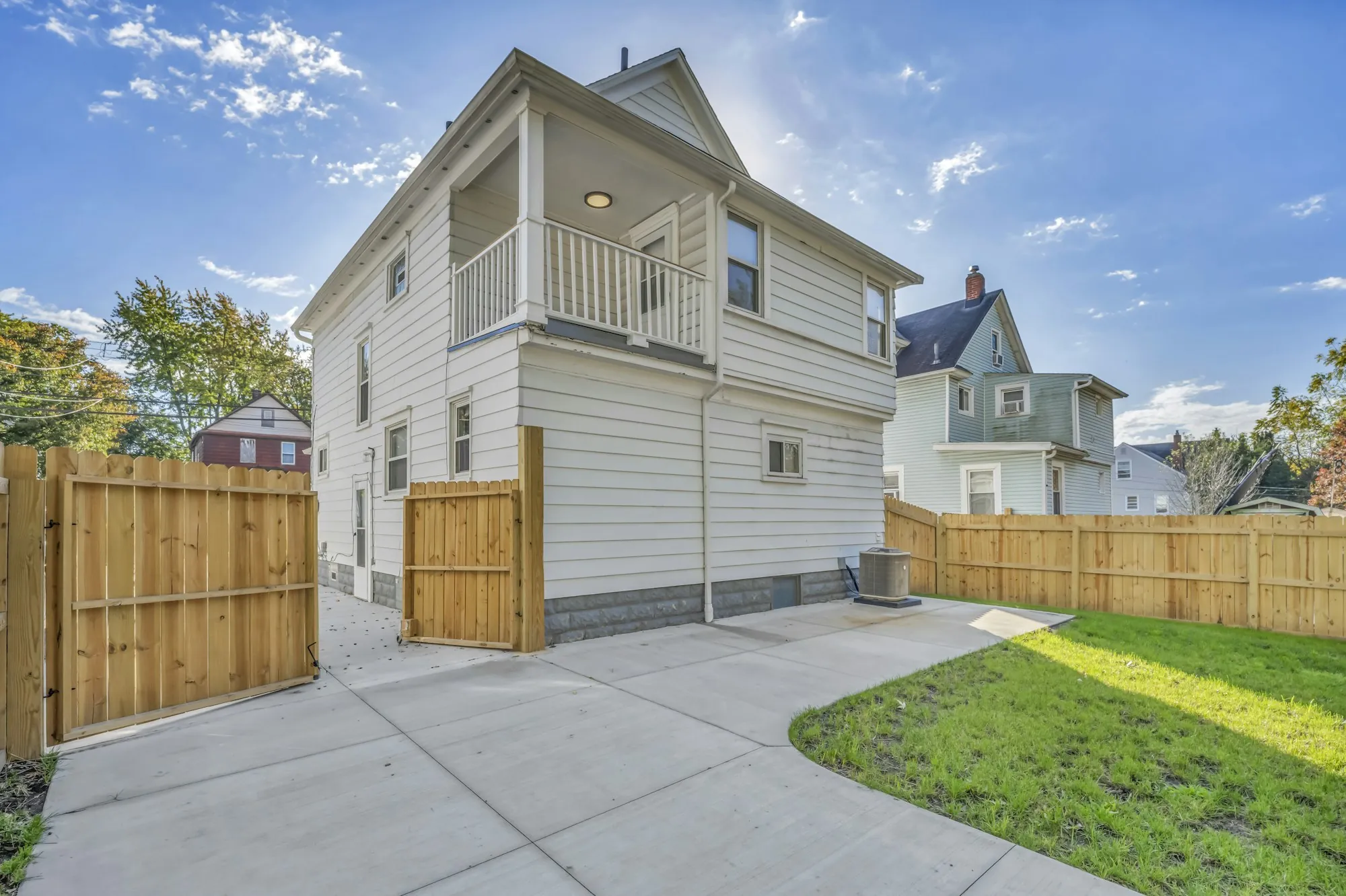 Two-story house with a long concrete driveway beside a wood fence